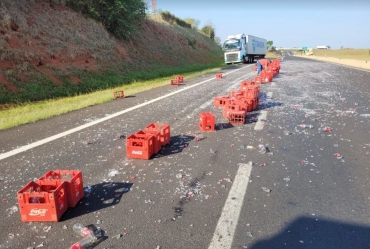 Caixas de garrafas de refrigerante caem de caminhão e ficam espalhadas em rodovia